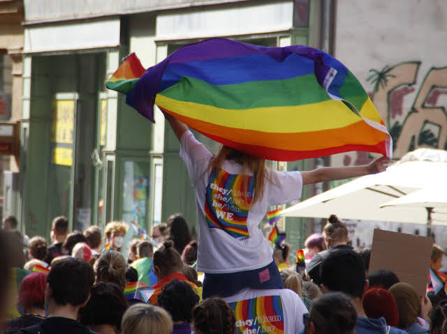 Teilnehmende der CSD-Demonstration in Halle; im Vordergrund wird eine große Regenbogenflagge geschwenkt.